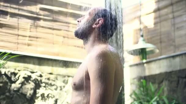 Чоловік стоїть під душем — стокове відео