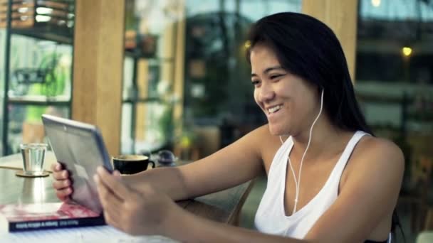Женщина смотрит кино на планшетном компьютере в кафе — стоковое видео