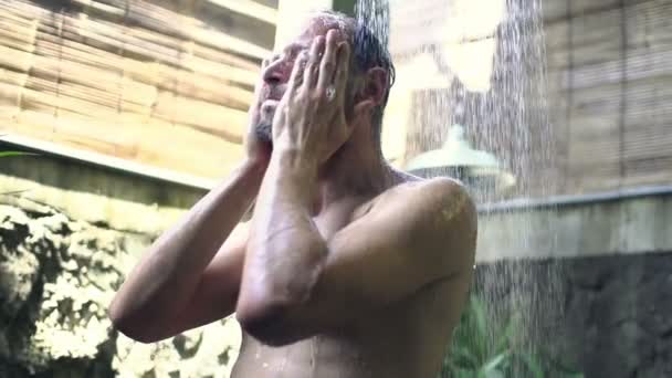 Чоловік миє обличчя під душем — стокове відео