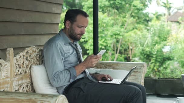 Homem de negócios comparando dados no smartphone e laptop — Vídeo de Stock