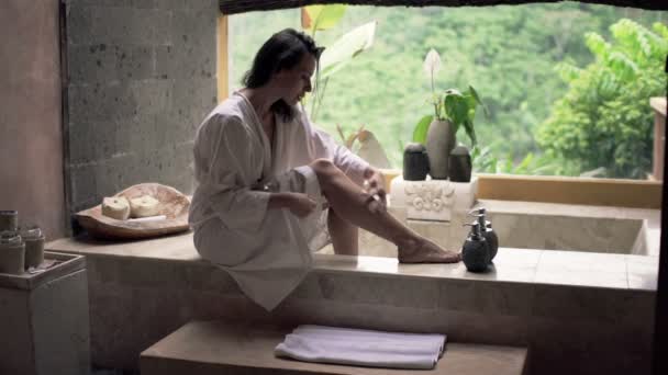 Женщина наносит лосьон увлажняющий крем на ногу — стоковое видео