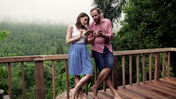 Pareja en la terraza usando teléfonos inteligentes — Vídeo de stock