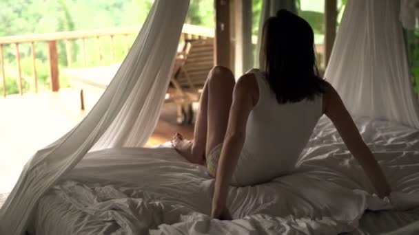 Женщина встает с кровати и просыпается на террасе — стоковое видео