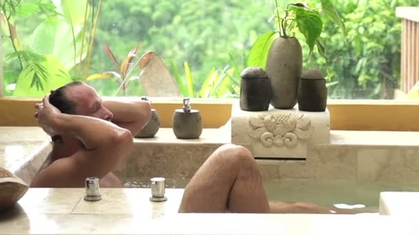 Молодой, красивый мужчина расслабляется в ванной — стоковое видео