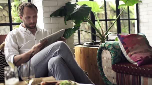 Мужчина читает газеты и пьет коктейли — стоковое видео