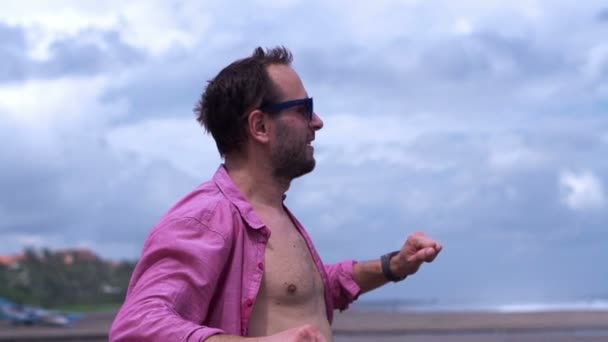 Человек, вытягивающий руки на пляже — стоковое видео