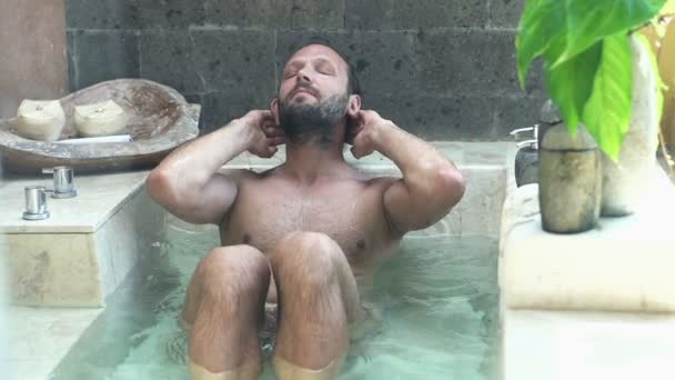 Молодой человек отдыхает в ванной — стоковое видео