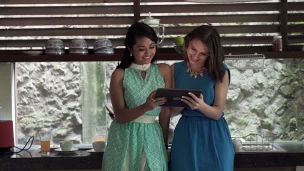 Девушки смотрят кино на планшетном компьютере на кухне — стоковое видео