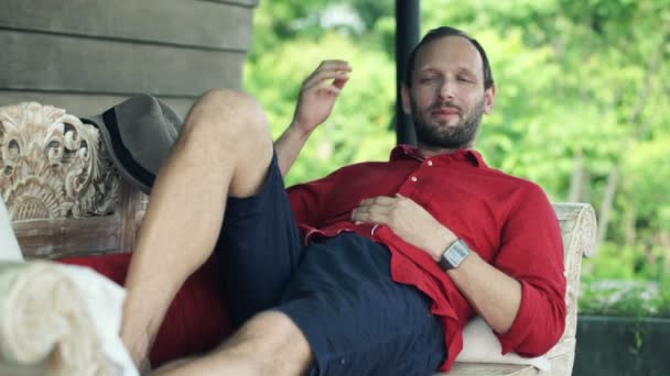 Hombre en sofá en terraza — Vídeos de Stock