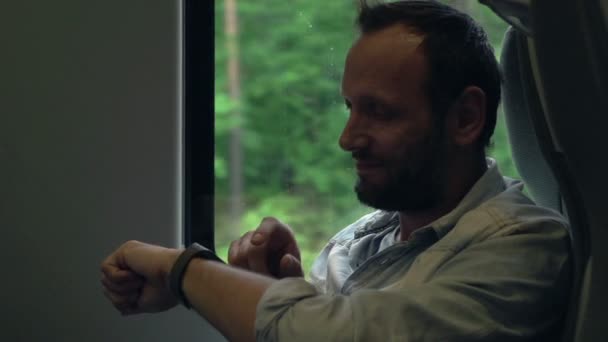 Joven con reloj inteligente sentado en un tren — Vídeos de Stock