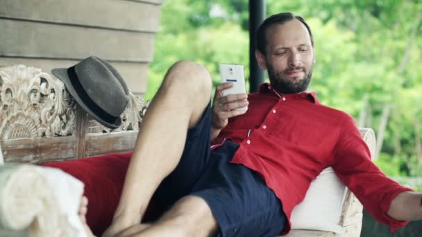 Hombre usando teléfono inteligente y bebida — Vídeos de Stock