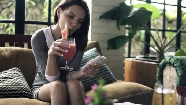 Businesswoman using smartphone and drinking cocktail — Stock Video