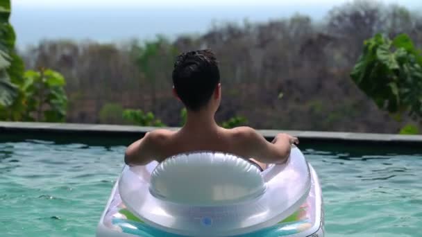 Adolescent relaxant sur matelas flottant dans la piscine — Video