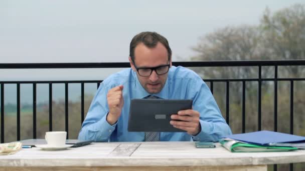 Бизнесмен читает новости с фондового рынка на своем планшете — стоковое видео