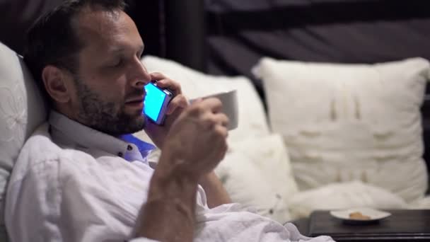 Man talking on cellphone and relaxing on bed — Stock Video