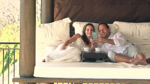 Pareja tomando fotos con teléfono celular en la cama gazebo — Vídeos de Stock