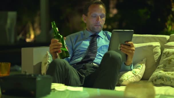 Uomo d'affari leggere articolo su tablet e bere birra — Video Stock