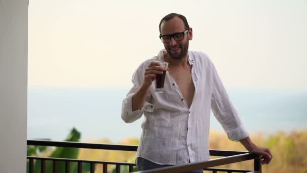 Щасливий чоловік виховує тости з напоєм на терасі — стокове відео