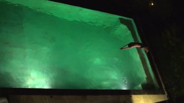 Menino pulando na piscina à noite — Vídeo de Stock