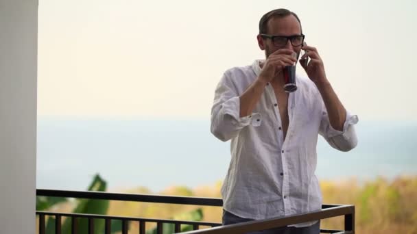 Чоловік розмовляє на мобільному телефоні і п'є каву — стокове відео