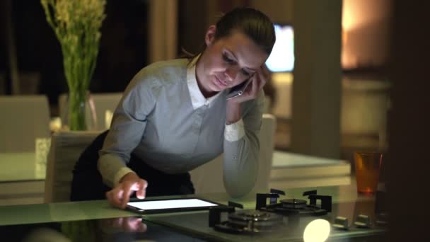 Mujer de negocios con teléfono celular y tableta en la cocina — Vídeos de Stock