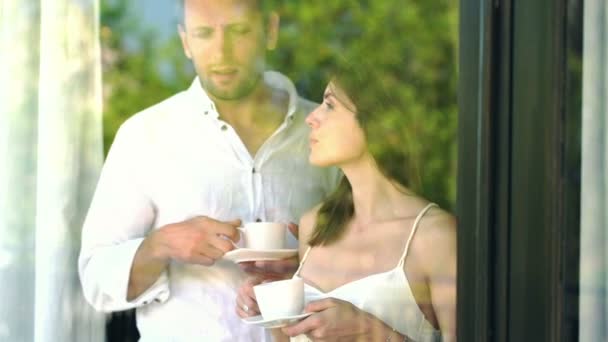 Пара розмовляє і п'є каву біля вікна — стокове відео