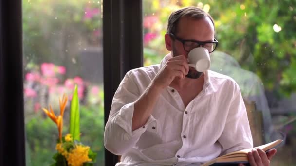 Hombre leyendo libro y bebiendo café — Vídeo de stock