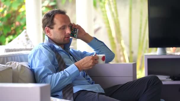 Businessman talking on cellphone and drinking tea — Stock Video