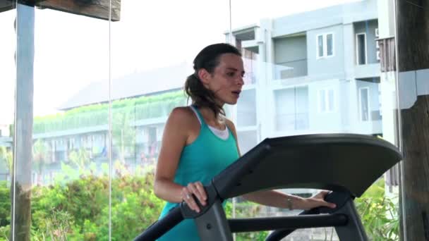 Vrouw draait op loopband in de sportschool — Stockvideo