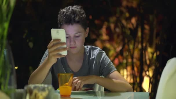 Adolescent manger sandwich et en utilisant smartphone — Video