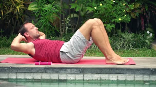 Uomo facendo sit-up sdraiato sul tappeto in giardino — Video Stock