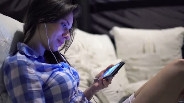 Kvinnan tittar på film på smartphone på sängen — Stockvideo