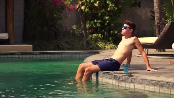 Adolescente relajante y tomar el sol en el borde de la piscina — Vídeo de stock