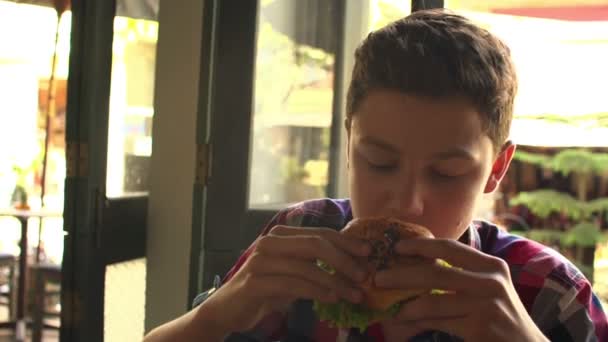 Adolescente comendo hambúrguer no restaurante fast food — Vídeo de Stock