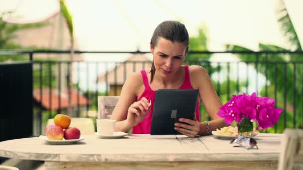 Mujer leyendo algo en la tableta y comiendo bocadillos — Vídeo de stock