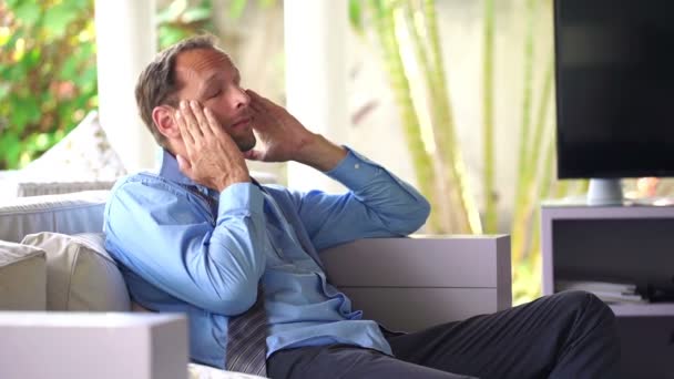 Уставший бизнесмен с головной болью на диване — стоковое видео