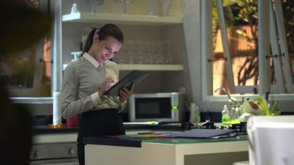 Mujer de negocios que trabaja en el ordenador tableta en la cocina — Vídeos de Stock