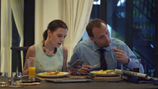 Pareja de negocios comiendo comida y usando smartphone y tableta — Vídeos de Stock