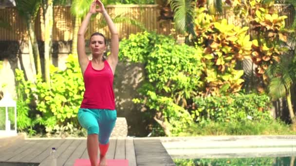 Vrouw doet yoga pose op de mat in de tuin — Stockvideo