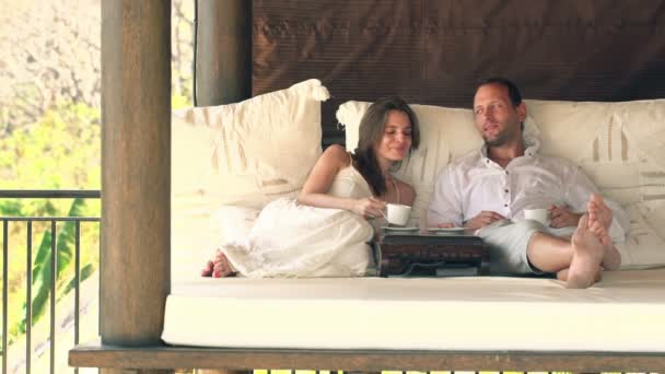 Couple enjoying coffee on gazebo bed — Stock Video