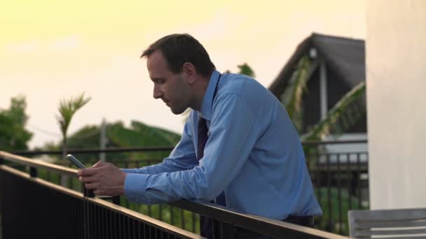 Geschäftsmann verschickt SMS auf Smartphone auf der Terrasse — Stockvideo