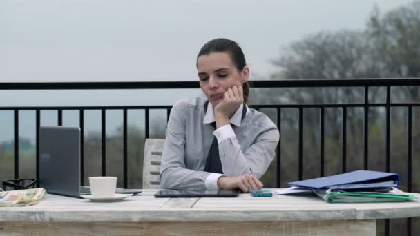 Perezosa mujer de negocios sentada junto a la mesa en la terraza — Vídeo de stock