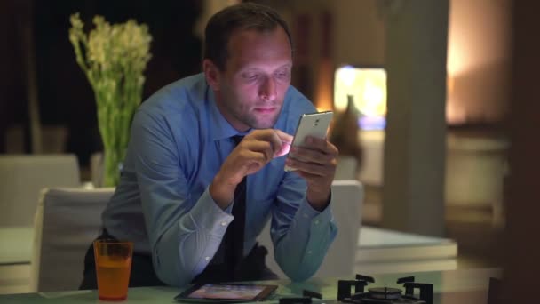 Geschäftsmann verschickt SMS auf Smartphone in Küche — Stockvideo
