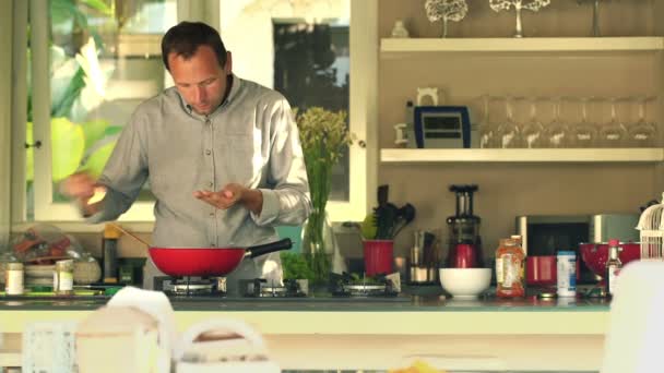 Mann kocht und würzt in Küche — Stockvideo