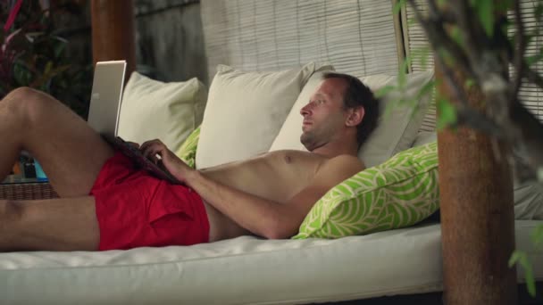 Człowiek z laptopa siedząc na łóżku altanka — Wideo stockowe