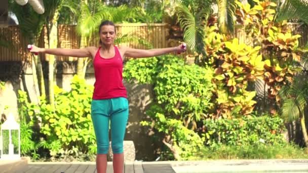 Mujer haciendo ejercicio con mancuernas en la estera en el jardín — Vídeos de Stock