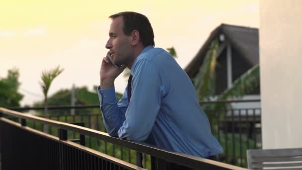 Empresario hablando por teléfono celular en la terraza por la noche — Vídeo de stock