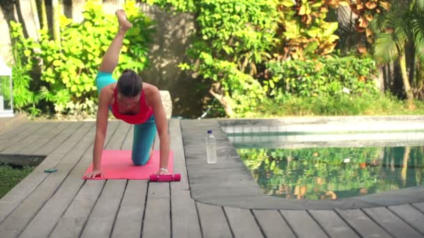 Žena, která dělá nohu cvičení na podložce v zahradě — Stock video
