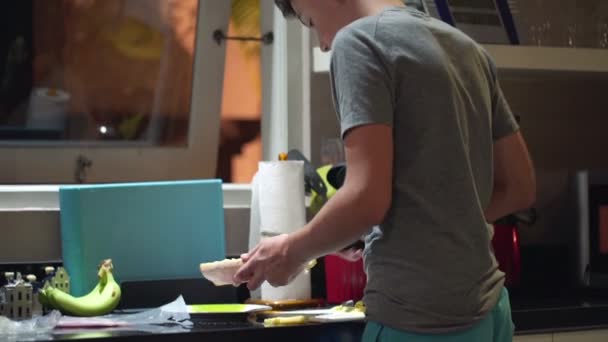 Adolescente preparando sándwich en la cocina por la noche — Vídeo de stock