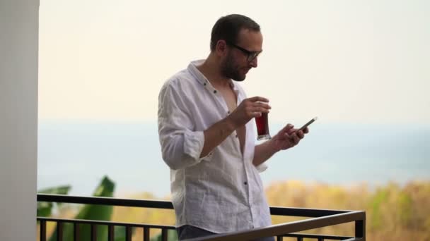 Hombre enviar SMS en el teléfono inteligente en la terraza — Vídeos de Stock